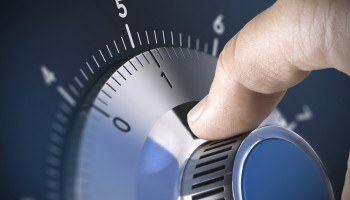 Close-up of hand rotating the dial of a combination safe lock.