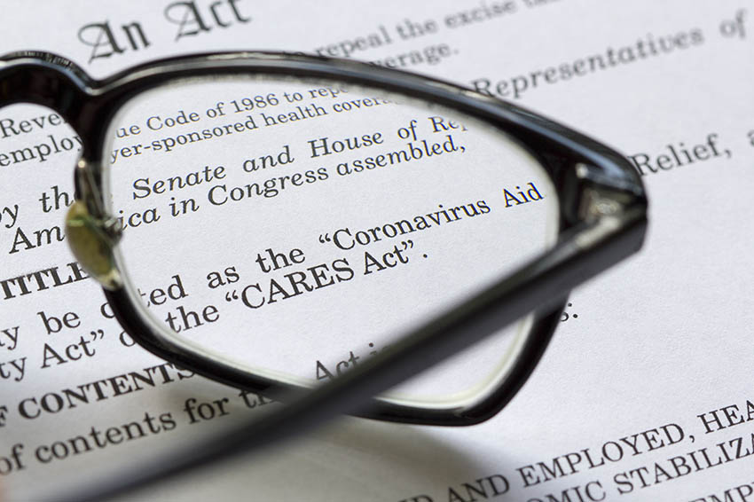 Closeup of the Coronavirus Aid, Relief, and Economic Security Act documents laying on a desk with eye glasses